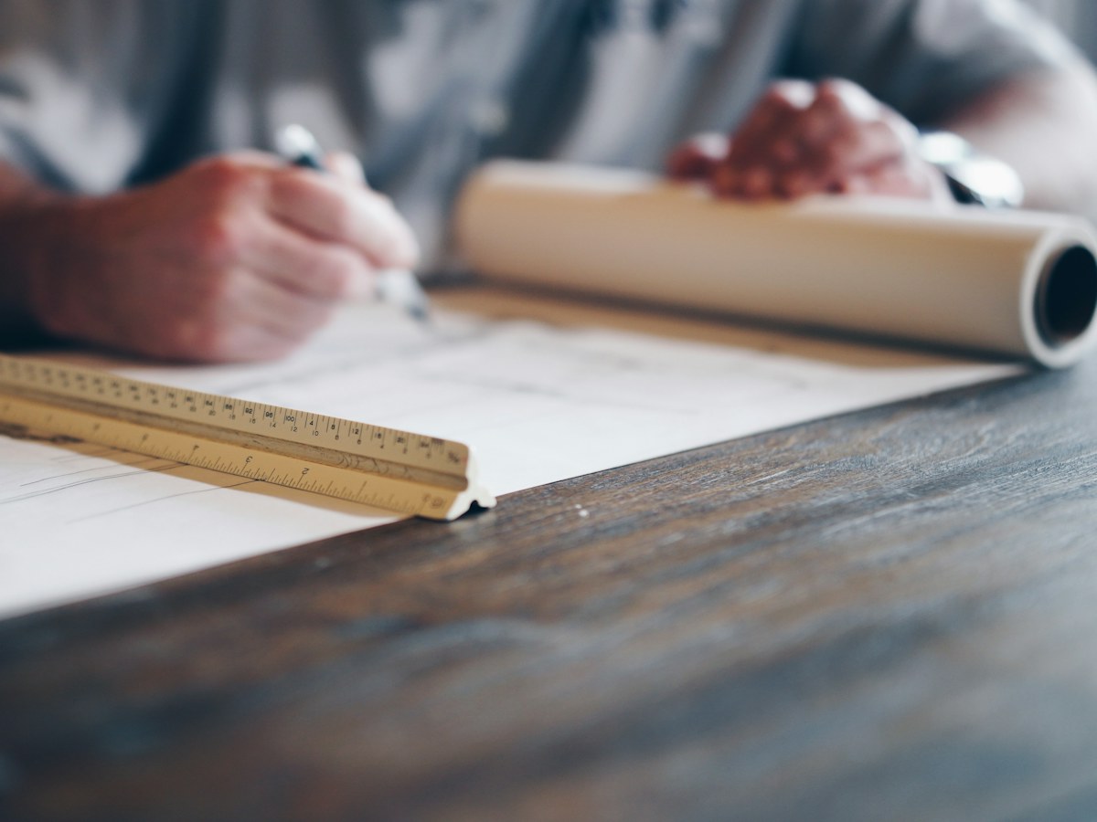 Hands drawing on architectural plans at a desk